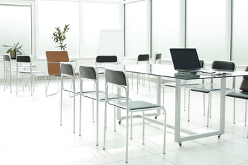 Flipchart laptop chairs and glass table in a bright office space
