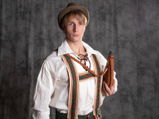 A young man in a national Bavarian suit with shorts on suspenders and a hat.