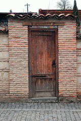 Fototapeta na wymiar Wooden door with a round metal handle on the brick wall
