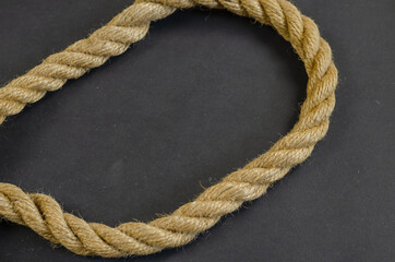 Hemp rope on a black background. Twisted rope is made of natural materials. Nautical theme.