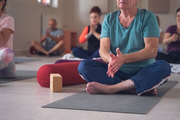 group, of different ages, in a yoga class, rubbing their hands together before beginning the...