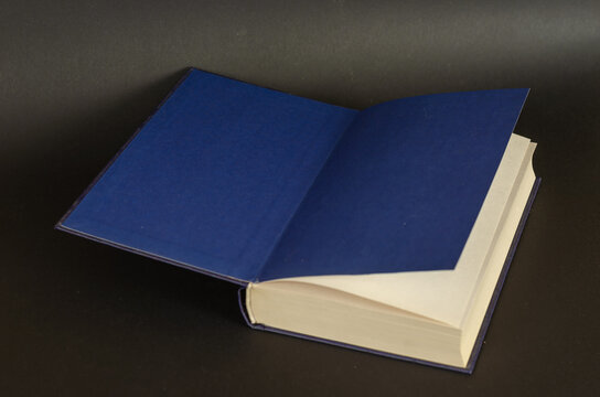 Open book on a black background. Textbook with blue endpapers. Hardcover. Knowledge, reading. Selective focus.