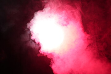 Artificial magic smoke in red light on black background