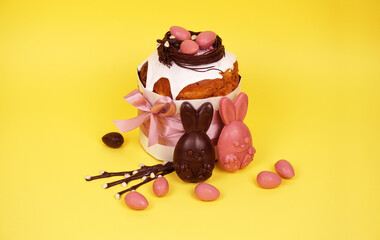 Beautiful Easter composition with Easter cake, chocolate eggs and a hare on a colored background, space for text.
