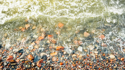 Sea waves slam into the sea rocks on the shore, sea foam on the shore rocks