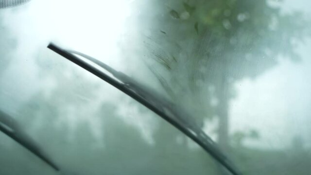 The view from the front window of the car with working windshield wipers during heavy rain while moving.