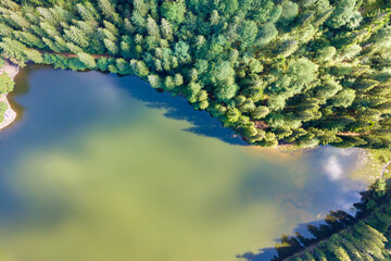Top down aerial view of big lake with clear blue water between high mountain hills covered with...