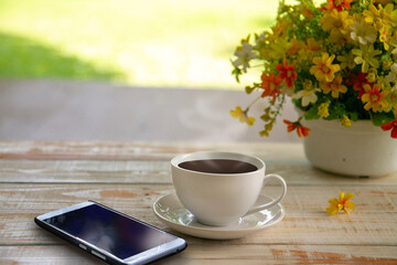 Mobile phone and a cup of coffee on wood texture background,