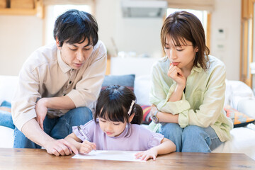 Obraz premium 家でお勉強をする女の子と両親
