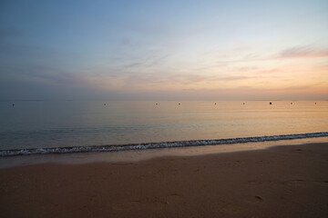 Fototapeta na wymiar Calm sea shore with crushing waves on sandy beach at sunrise.