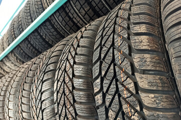 Many black rubber car tires on store shelf for sale.