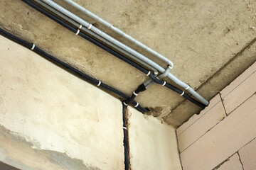Electrical cables laid in protective corrugation installed on the ceiling and wall in a room under...