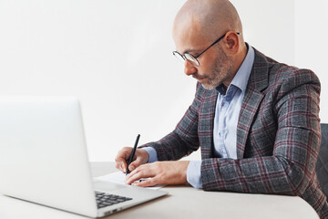 Adult man in a suit writing in a document at the workplace