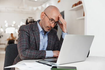 Pensive businessman looking at laptop while sitting in cafe