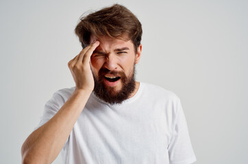 bearded man health problems migraine stress disorder light background