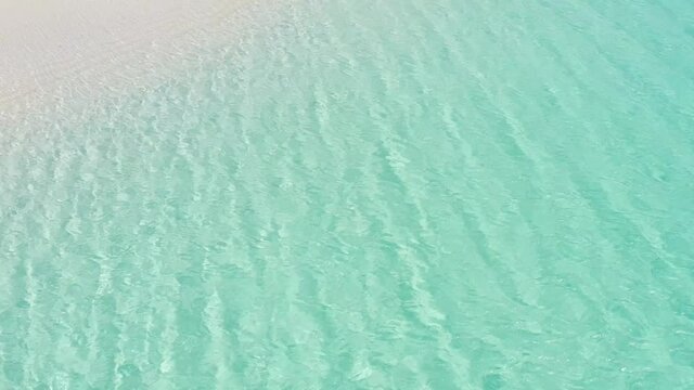 Blue color seawater near a white sand beach landscape. Sea waves on white coral sand. Caribbean beach landscape.