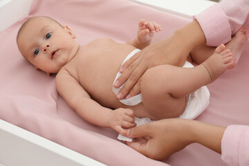 Mother changing her baby's diaper on table