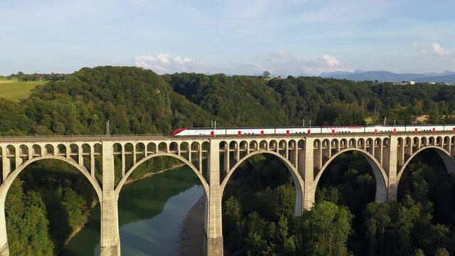Aerial drone footage of a train crossing the famous Granfey viaduc, or bridge, over the Sarine river in Fribourg, Switzerland