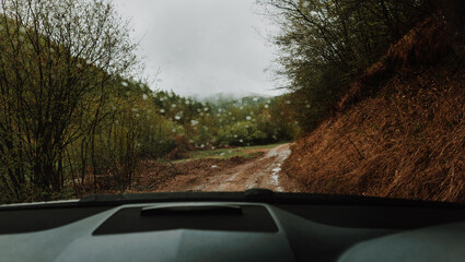 POV inside car windshield view point. Driver driving a modern off road right hand drive RHD car on the mountain forest dirty country road. Face reflecting in inside mirror.Safely auto driving concept © Soloviova Liudmyla