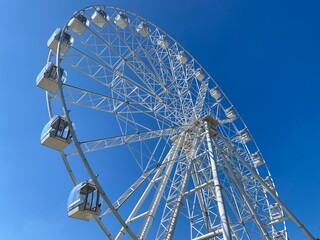 White Ferris wheel against the blue sky on a sunny day. The idea of ​​vacations, relaxation and entertainment