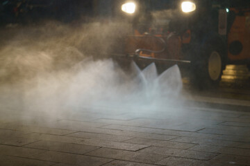 Street cleaning machine working in night. Сleaning the road with pressurized water. Using water for city street washing 