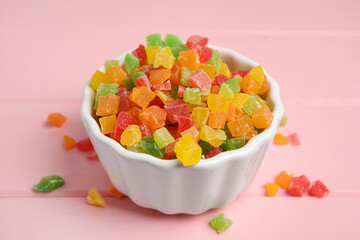 Mix of delicious candied fruits in bowl on pink wooden table