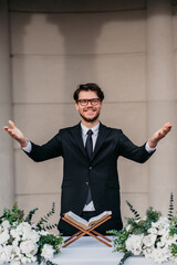 Portrait of young cheerful Caucasian marriage officiant during wedding ceremony
