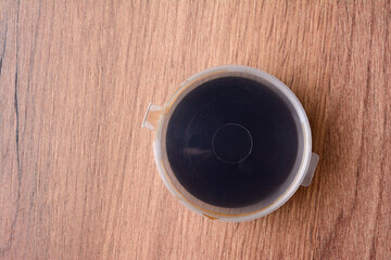 Soy sauce in a transparent plastic container. On the background of a wooden texture, top view