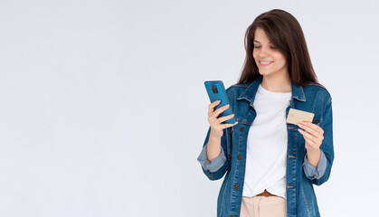 Image of excited young lady isolated over white background using mobile phone holding credit card.