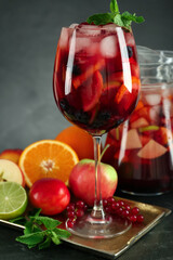 Glass and jug of Red Sangria with fruits on black table