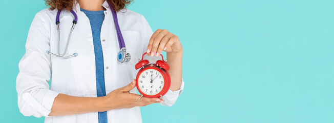 Woman doctor holding an alarm clock isolated on blue background