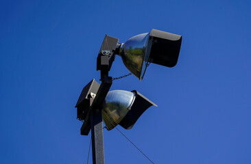 Closeup of street projectors on a metal pole isolated on blue background