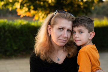 The woman took her little son from school and together they return home in the evening, talk, hug. Portrait of a happy woman with a little son