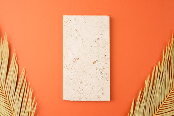 Natural stone for the presentation of jewelry and cosmetics. Storage Tray. Trending concept in natural materials with palm leaves on orange background. Presentation backdrop for text or advertising.