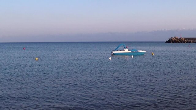 Recreational pedal boats along the shore at sundown. 4K