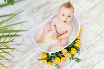 Obraz na płótnie Canvas a beautiful baby boy bathes in a bath with fruit lemons and smiles, the concept of hygiene and washing