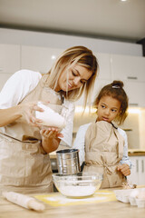 Obraz na płótnie Canvas Loving young mother or nanny teach little kid prepare food at home kitchen