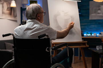 Senior artist with disability drawing vase design with pencil in artwork room at home. Caucasian...