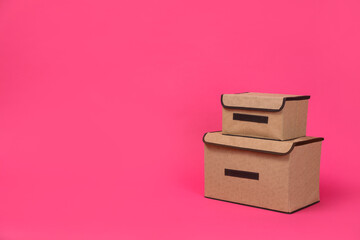 Two textile storage cases on pink background. Space for text