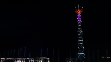 Glowing TV tower at night. Festive illuminated broadcast tower. Space for text. Long exposure.