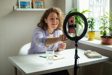curly woman talking with smartphone standing with led light for instagram blog blogger social