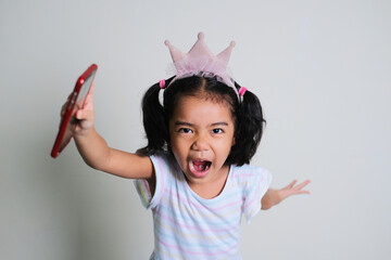 Asian little girl screaming while running forward with her hand holding mobile phone