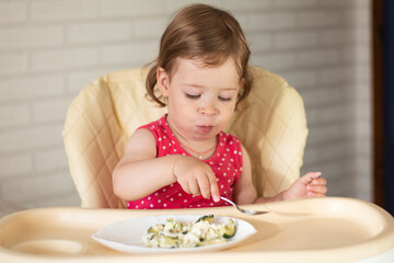 A small European child will eat a spoonful of vegetable and egg lasagna on their own. The baby...