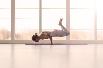 View of beautiful young woman working out in luxury fitness center, doing yoga or pilates exercise.