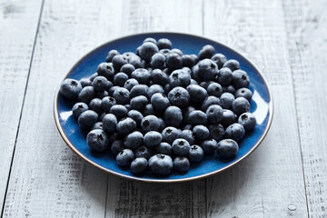 Blueberries on blue plate on wooden table
