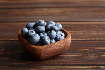 Bowl with fresh blueberries on wooden table