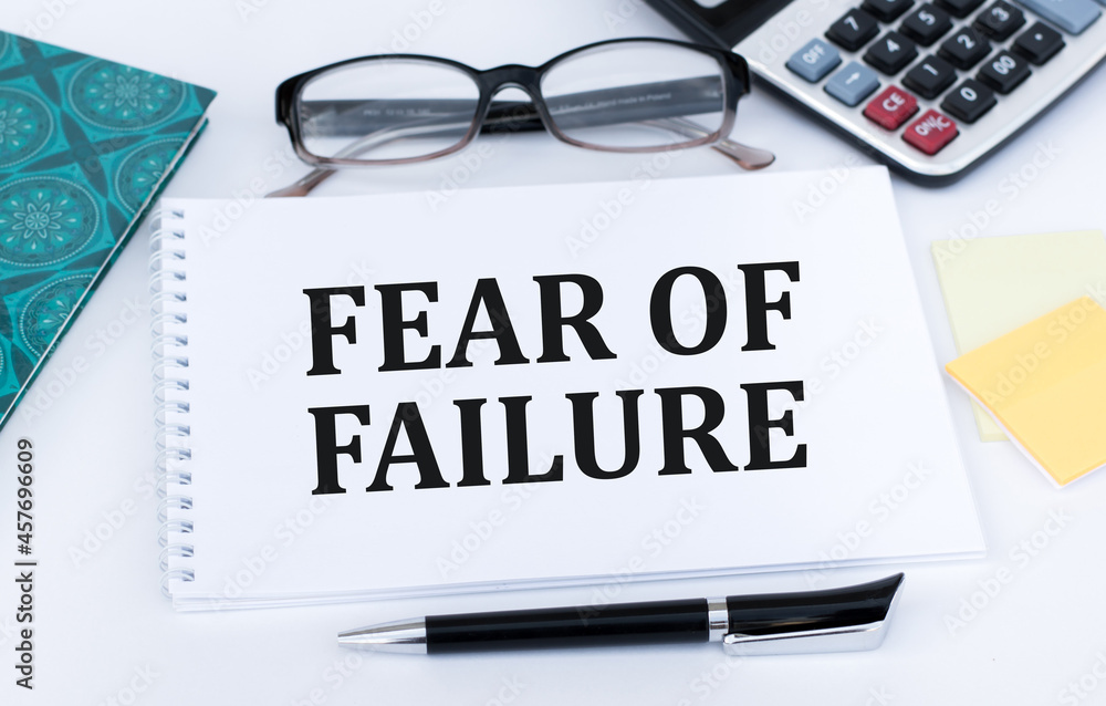 Poster text fear of failure inscription text on white notepad on office table.