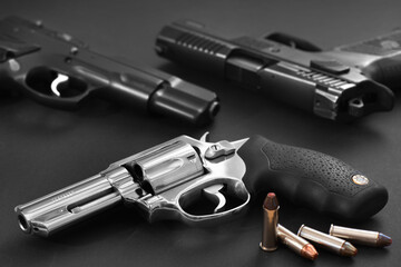 Chrome revolver with ammunition and two black pistols in the background.