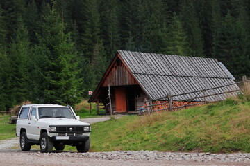 Auto 4x4 terenowe w górach, w tle górski domek drewniany.  Polskie Tatry Zachodnie. © jarizPJ