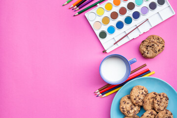 
Top view of snack with cookies biscuits, milk, ounces of chocolate and donuts, with blue and pink background, box of colored pencils and watercolors